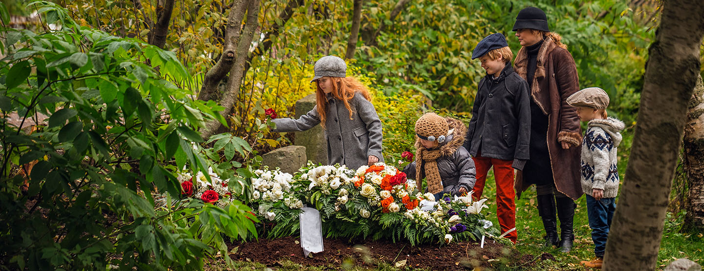 Family placing flowers on a grave site.